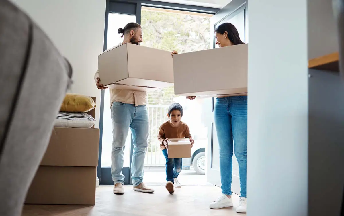 Family carrying boxes as they move into their new home